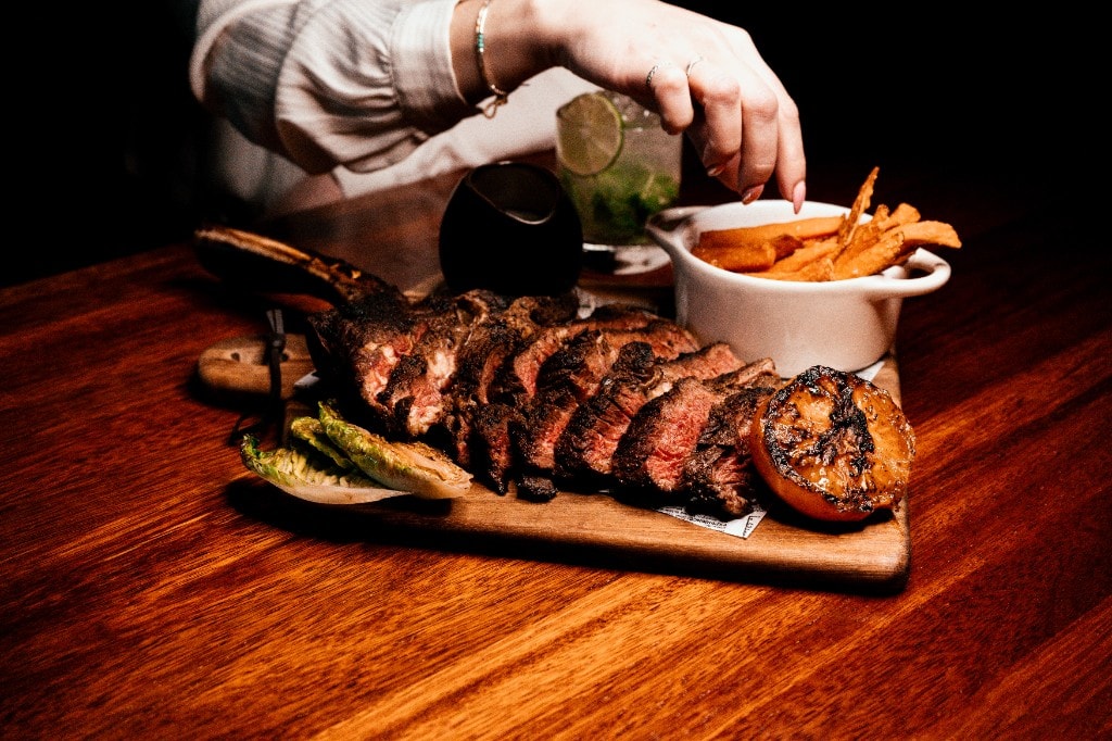 Tomahawk-steak servert på trefjøl i stemningsfullt lys