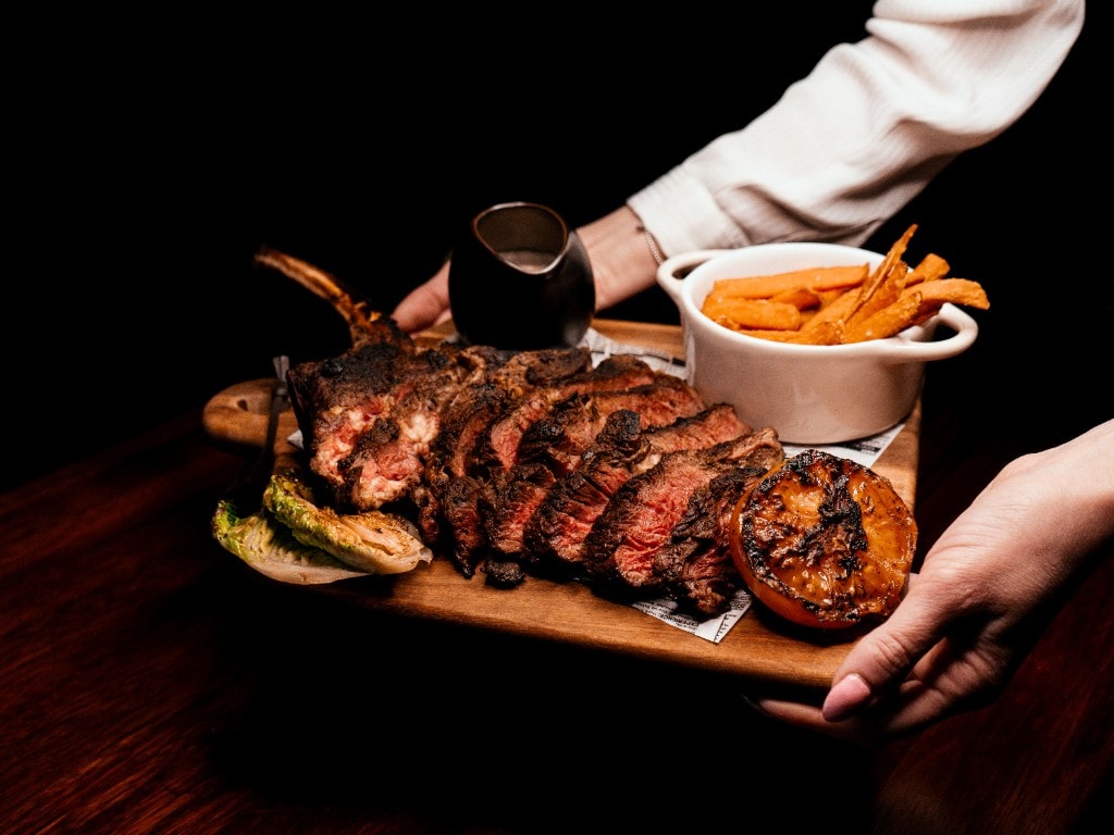 Tomahawk-steak på fjøl fotografert ovenfra