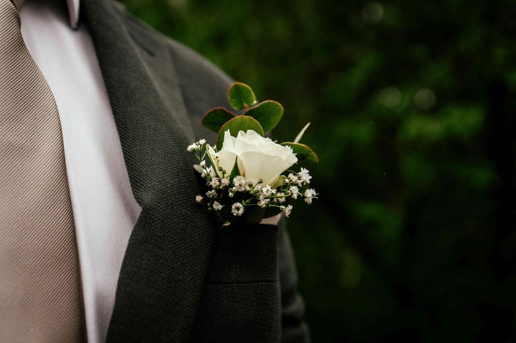Nærbilde av knapphullsblomst med hvit rose og brudeslør